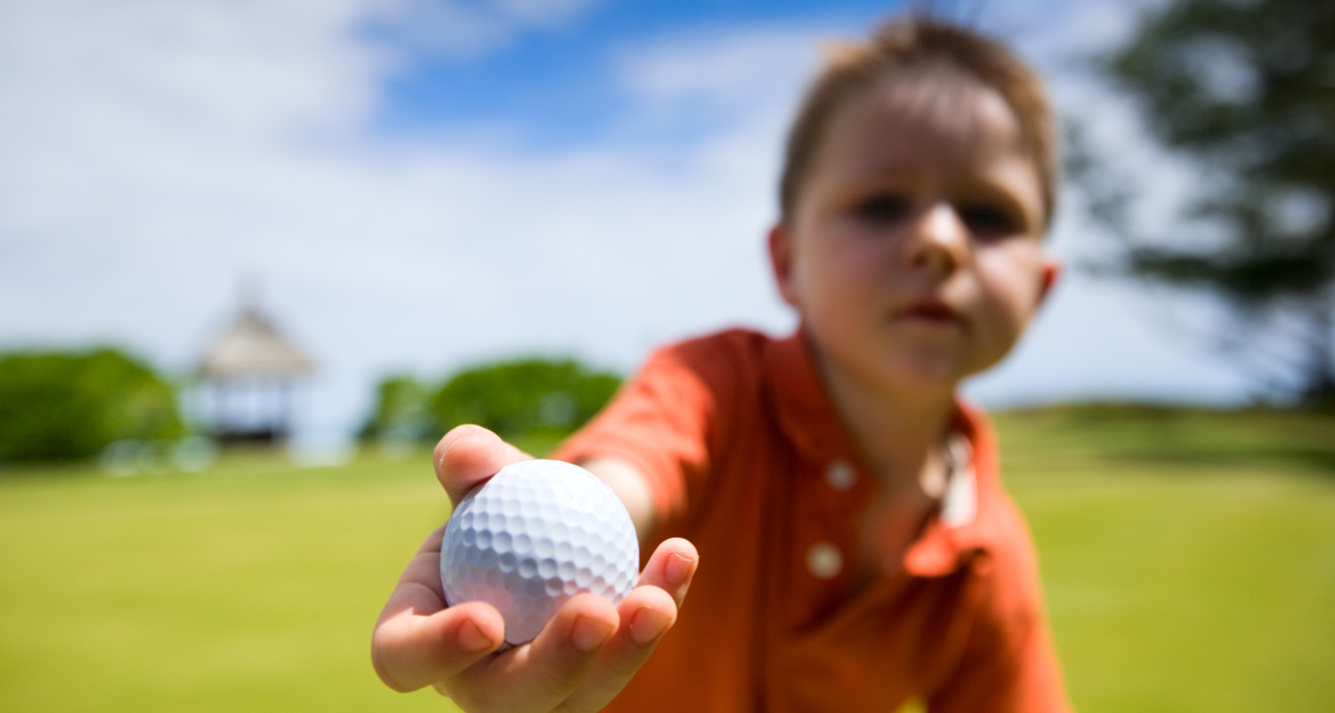 Pojke som håller fram en golfboll