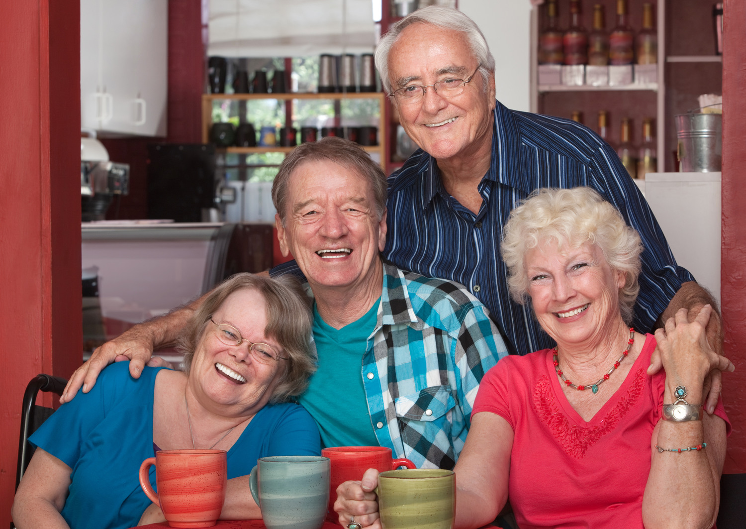 Fyra glada årsrika personer som sitter på ett café
